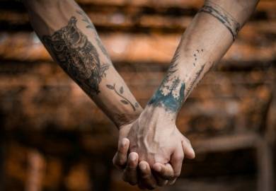 paar mit tattoos hält händchen beim wandern