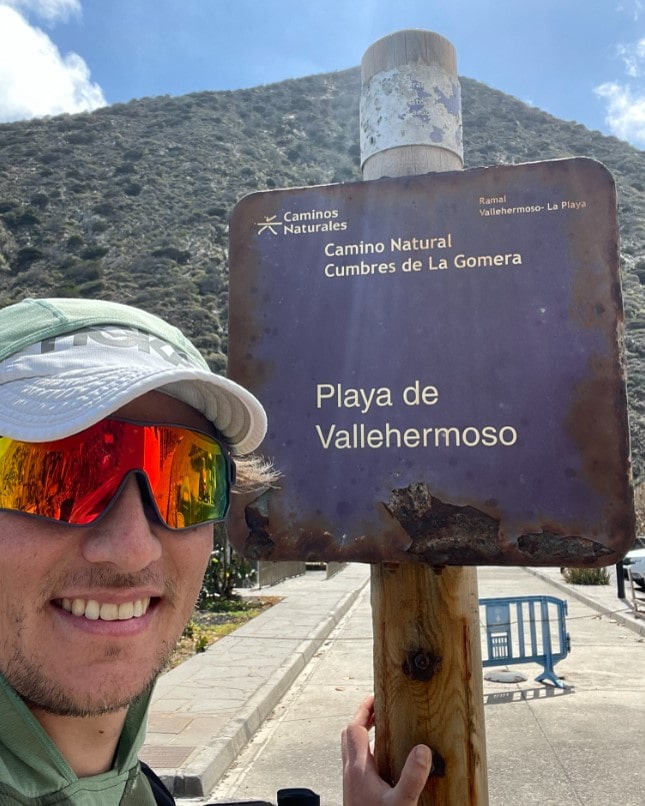 Zeichen des Camino Natural Cumbres de La Gomera am Playa Vallehermoso mit Wanderer als Selfie von Lucas Beyerling von TrailNation auf dem GR 131